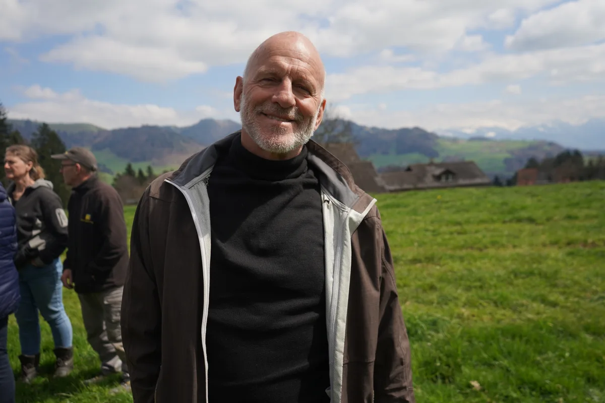 Ein Mann in Mitten der Natur strahlt in die Kamera.